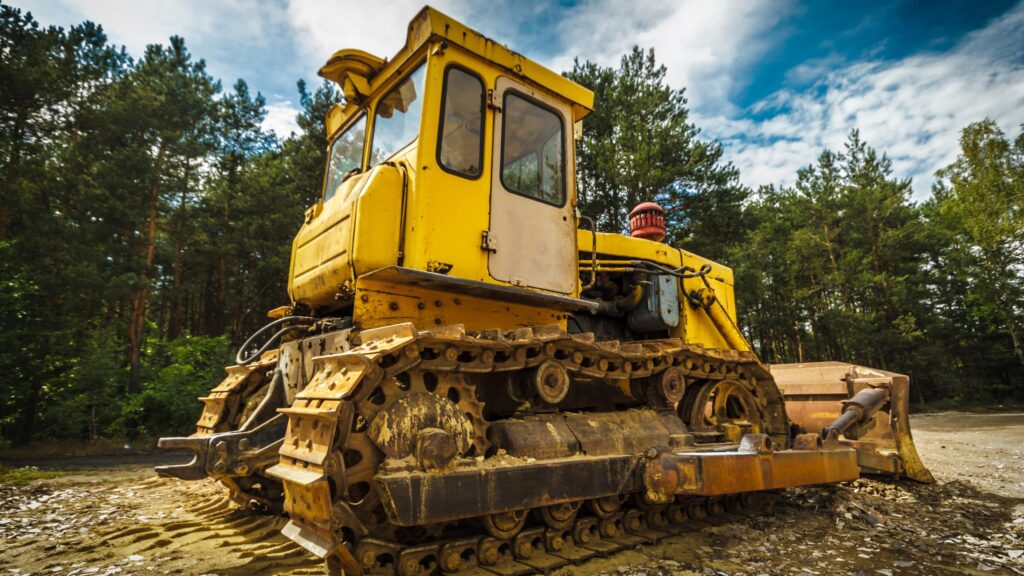 a large yellow bulldozer sitting on top of a dirt field