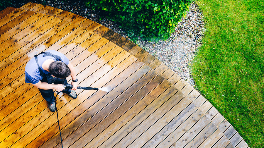 cleaning terrace with a power washer - high water pressure cleaner on wooden terrace surface